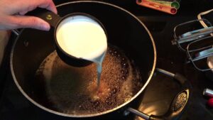 cream is being added to the pot of boiling maple syrup