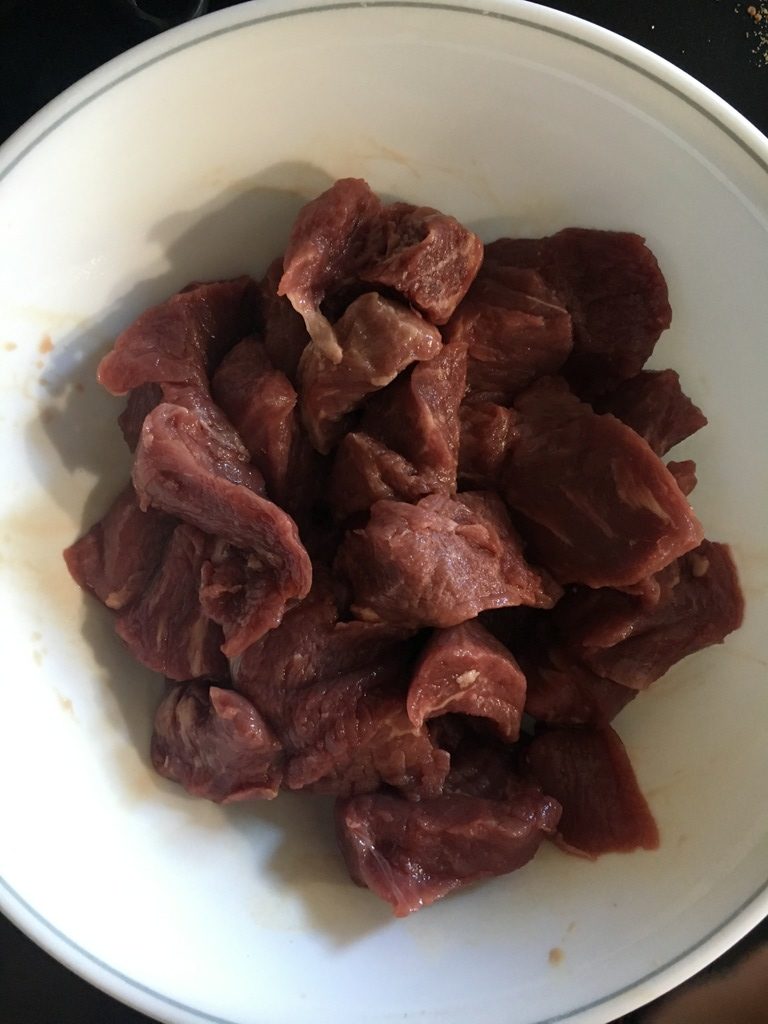 Uncooked stewing beef on a white plate
